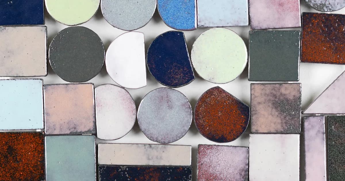 Arranged ceramic tiles and circular discs in muted pastels, rusts, and grays with weathered patina surfaces, creating a geometric mixed-media composition.