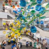 UrbanGlass gallery interior with large hanging glass spheres in yellow and blue suspended from ceiling.