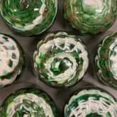 Six clear glass vessels with spiral green and white botanical or organic patterns inside, viewed from above.