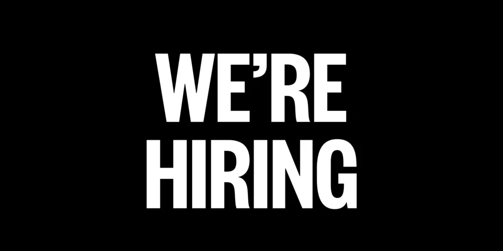 White sans-serif text reading "WE'RE HIRING" on solid black background.