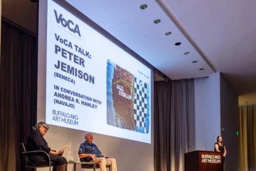 VoCA Talk presentation event with panelists seated on stage, projection screen displaying speaker information, Buffalo AKG Art Museum venue.