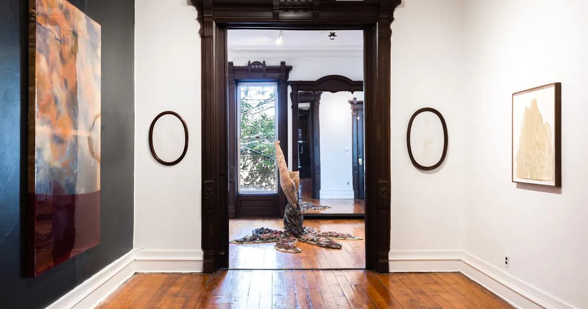 Interior of Welancora Gallery showing white walls with framed artworks, a wooden doorway leading to a room with a sculpture, and hardwood floors
