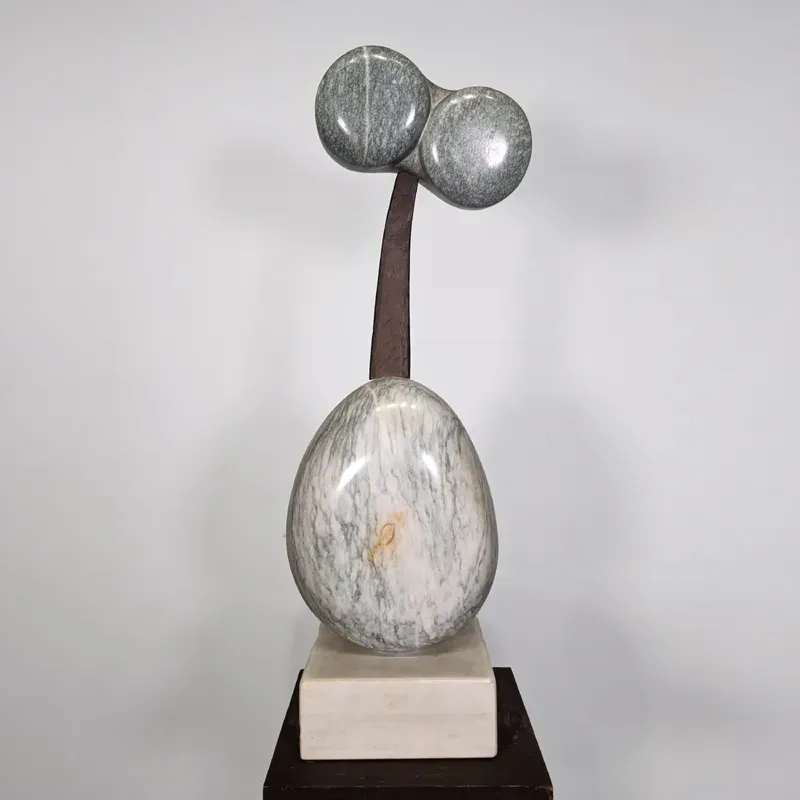 Sculptural artwork: metallic spheres on a stem rising from a larger egg-shaped form mounted on a black and white base.