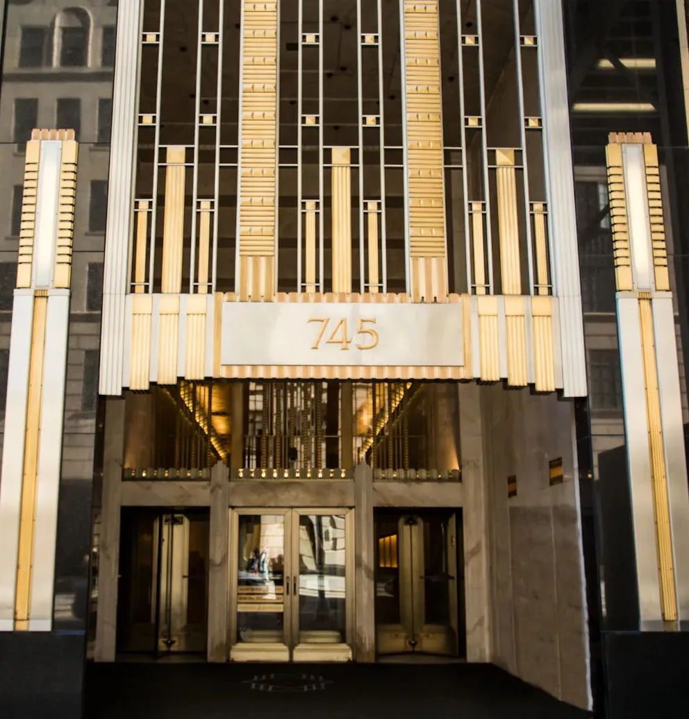Art Deco style building facade with gold fluted columns and glass entrance doors, marked with the address 745